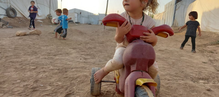 Despite the baking summer sun, IDP kids play on sand, sunk in dust